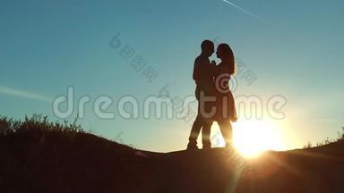 情侣在夕阳下剪影亲吻拥抱.. 慢动作视频。 年轻夫妇在日落时接吻。 男人和女孩见面